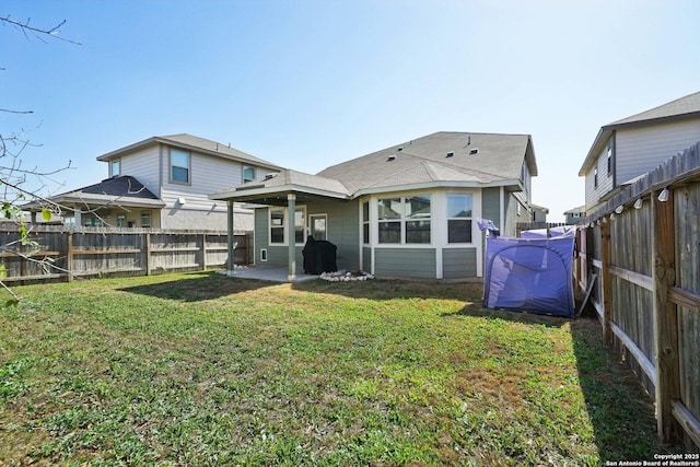 back of property with a fenced backyard, a lawn, and a patio