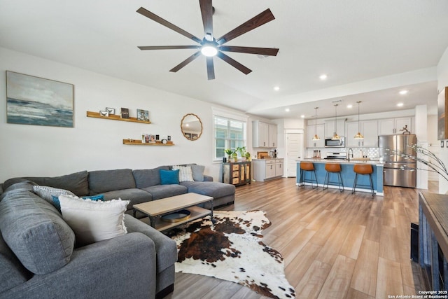 living area with lofted ceiling, light wood finished floors, a ceiling fan, and recessed lighting