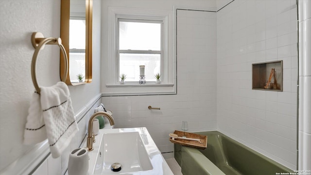 full bathroom featuring a bathing tub, tile walls, and a sink