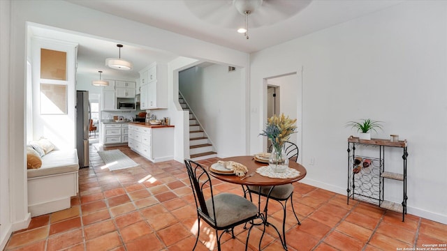 dining space featuring light tile patterned floors, stairs, and baseboards