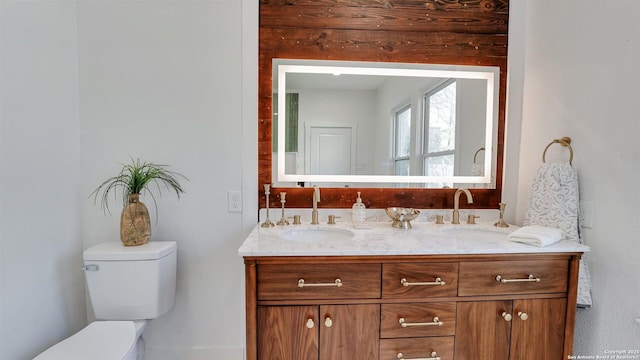 bathroom with toilet, double vanity, and a sink