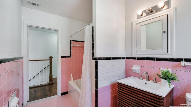 full bathroom with tile walls, visible vents, and vanity