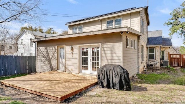 back of house with french doors, roof mounted solar panels, fence, stone siding, and a wooden deck