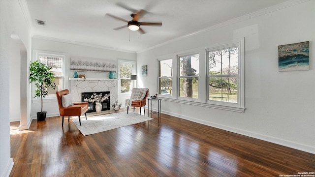 living area featuring baseboards, visible vents, ornamental molding, wood finished floors, and a fireplace