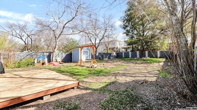 view of yard featuring a fenced backyard, an outdoor structure, a wooden deck, and a storage shed