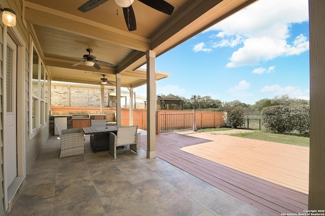 view of patio with a wooden deck, fence, and outdoor dining space