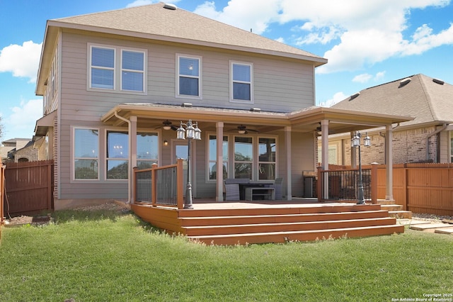 rear view of house featuring ceiling fan, fence, and a yard