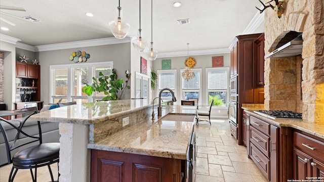 kitchen featuring stone tile floors, visible vents, a kitchen breakfast bar, appliances with stainless steel finishes, and a large island with sink