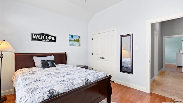 bedroom with lofted ceiling, a closet, baseboards, and wood finished floors