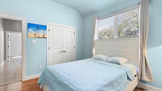 bedroom featuring vaulted ceiling, a closet, wood finished floors, and baseboards