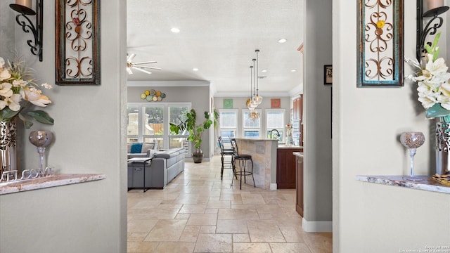 hallway featuring stone tile flooring, crown molding, a textured ceiling, and baseboards