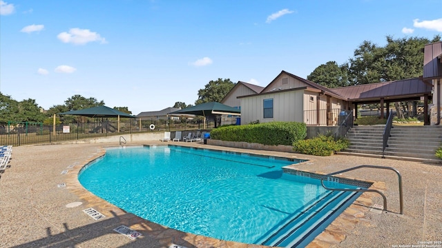 community pool featuring stairs, a patio, and fence