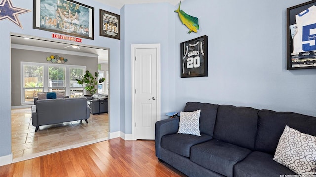 living room with baseboards, wood finished floors, and crown molding