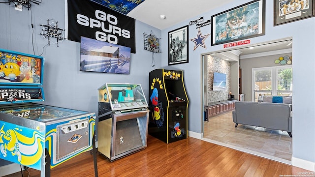 recreation room with baseboards, wood finished floors, and crown molding