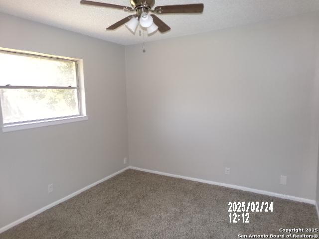 carpeted empty room featuring a ceiling fan, baseboards, and a textured ceiling