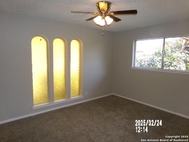 carpeted empty room featuring a textured ceiling, ceiling fan, and baseboards