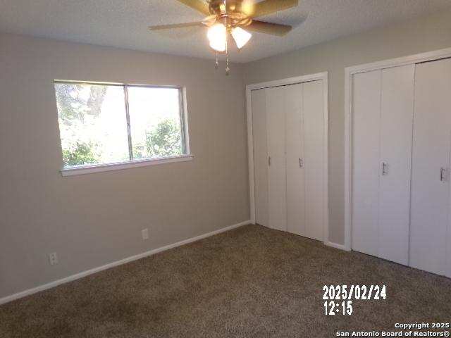 unfurnished bedroom with a ceiling fan, two closets, and carpet flooring