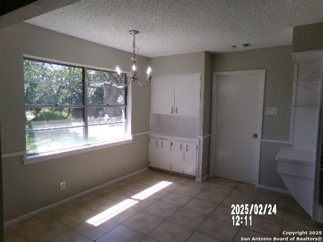 unfurnished dining area with a chandelier, a wealth of natural light, and a textured ceiling