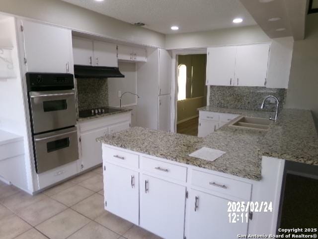 kitchen with black electric stovetop, stainless steel double oven, a sink, a peninsula, and under cabinet range hood