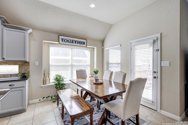 dining space with lofted ceiling, light tile patterned flooring, and baseboards