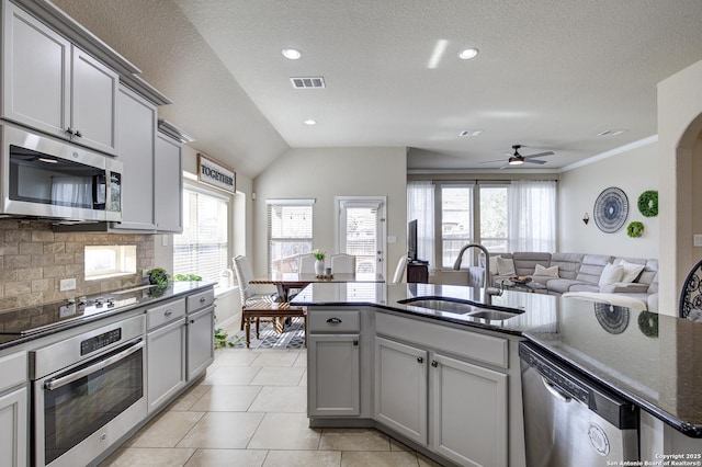 kitchen featuring a sink, visible vents, appliances with stainless steel finishes, backsplash, and dark stone countertops