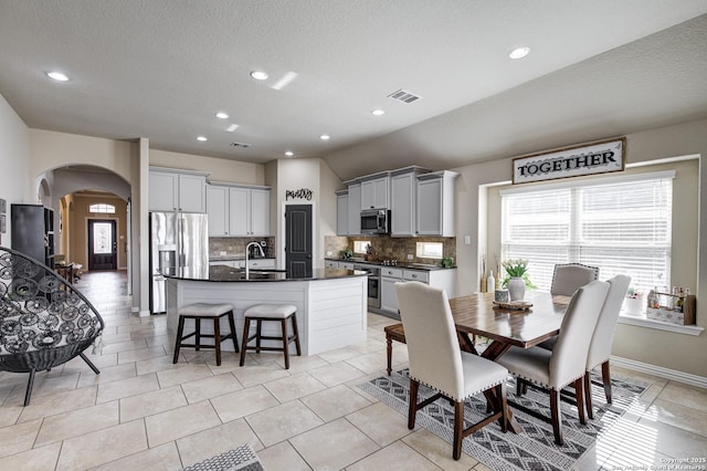 dining space with light tile patterned floors, baseboards, visible vents, arched walkways, and recessed lighting