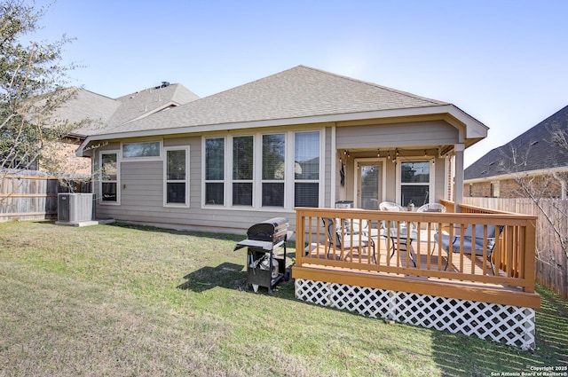 rear view of house with a yard, a shingled roof, central AC unit, fence, and a wooden deck