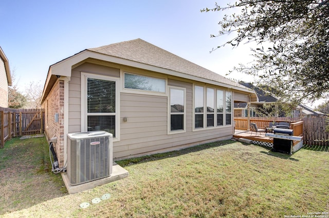 rear view of property featuring a shingled roof, a lawn, a fenced backyard, and central air condition unit