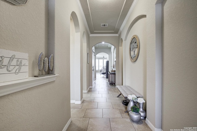 hallway with arched walkways, crown molding, visible vents, a textured wall, and tile patterned flooring