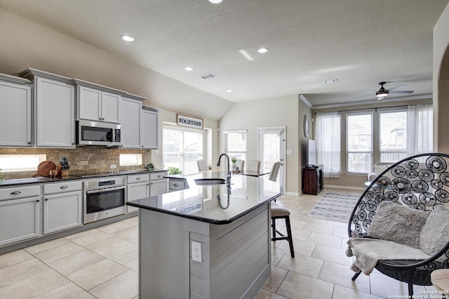 kitchen with a sink, visible vents, a kitchen breakfast bar, appliances with stainless steel finishes, and tasteful backsplash