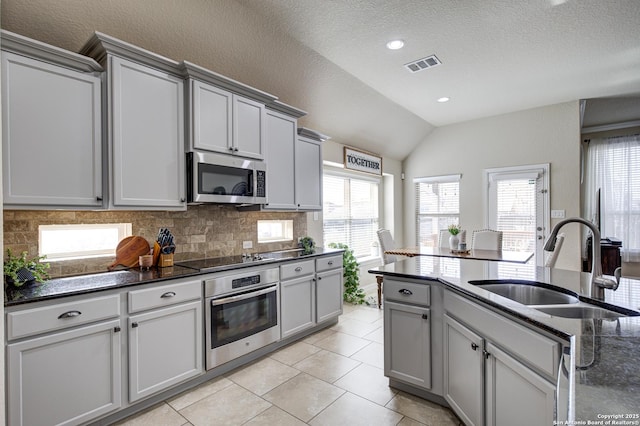 kitchen featuring visible vents, decorative backsplash, gray cabinetry, appliances with stainless steel finishes, and a sink