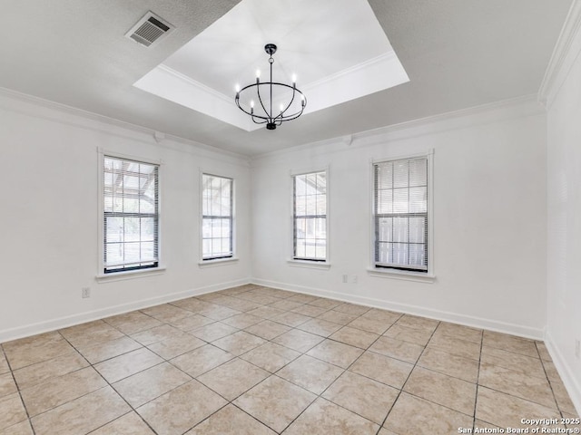 empty room with visible vents, a tray ceiling, a chandelier, and crown molding