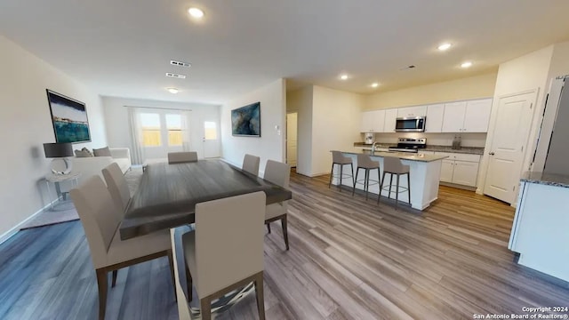 dining area with baseboards, visible vents, wood finished floors, and recessed lighting