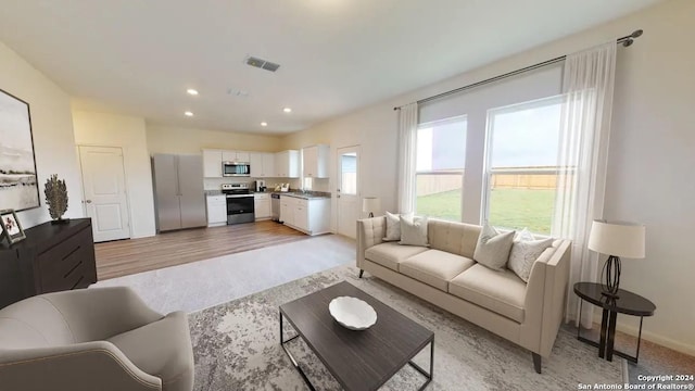 living area featuring light wood-style floors, baseboards, visible vents, and recessed lighting