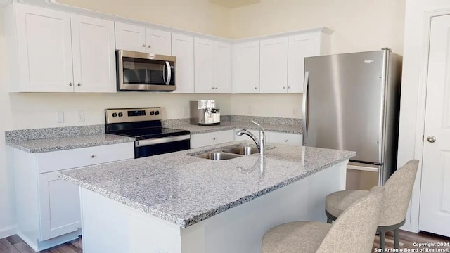 kitchen featuring appliances with stainless steel finishes, a sink, white cabinetry, and a kitchen breakfast bar