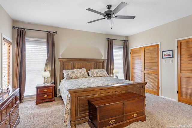 bedroom with multiple closets, light colored carpet, ceiling fan, and baseboards