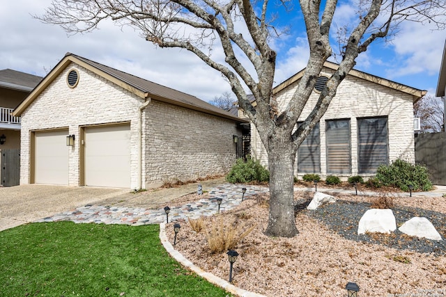 view of front facade with metal roof, fence, a garage, stone siding, and driveway