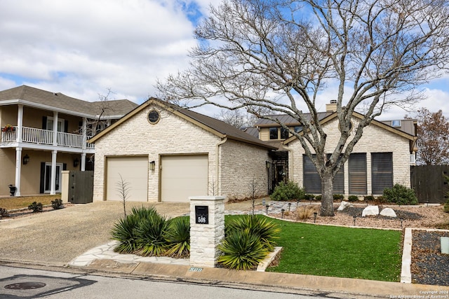 view of front of property with a chimney, an attached garage, a balcony, stone siding, and driveway