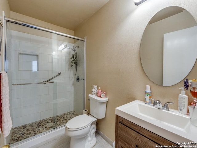 bathroom with baseboards, a shower stall, toilet, and vanity