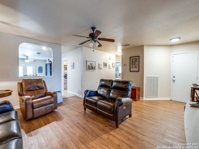 living area featuring washer / dryer, light wood-type flooring, visible vents, and ceiling fan