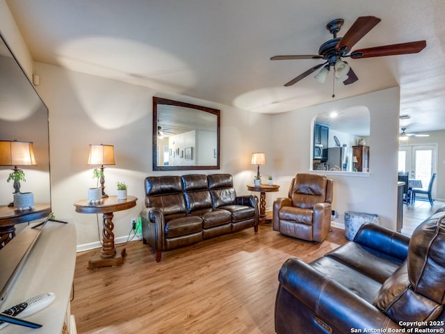 living area with ceiling fan, light wood-style flooring, and baseboards