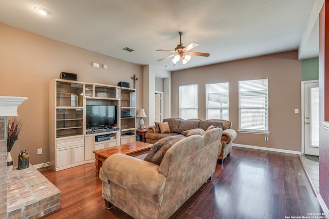 living room featuring a ceiling fan, dark wood finished floors, visible vents, and baseboards