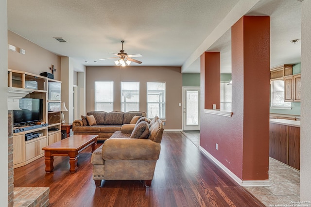 living area with a ceiling fan, wood finished floors, visible vents, and baseboards