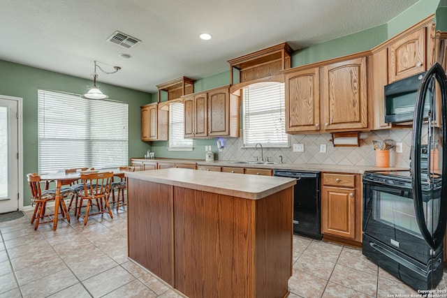 kitchen featuring a kitchen island, visible vents, a sink, light countertops, and black appliances