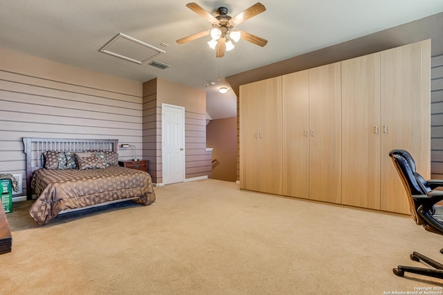 carpeted bedroom featuring attic access, wooden walls, visible vents, and ceiling fan