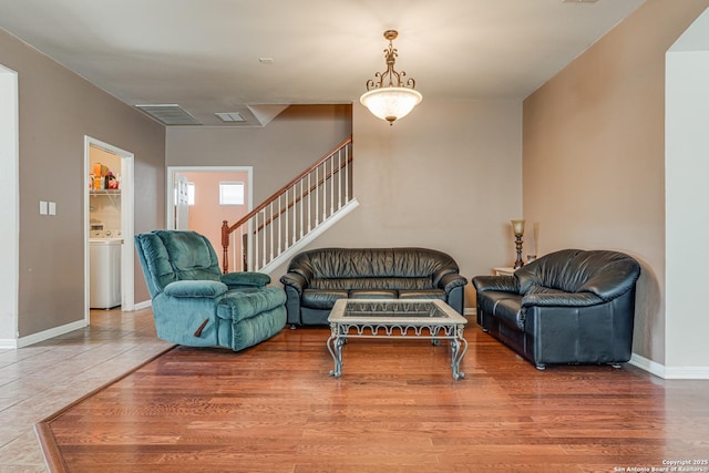 living area featuring stairs, washer / clothes dryer, wood finished floors, and baseboards