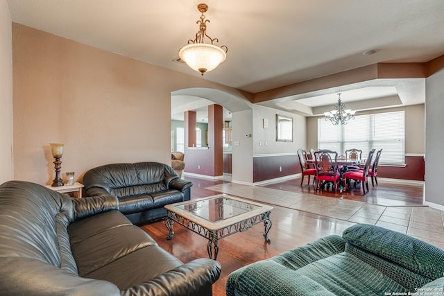 tiled living area with arched walkways, a tray ceiling, and baseboards