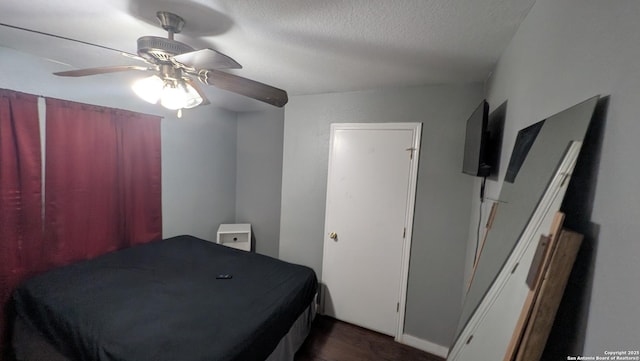 bedroom with a ceiling fan, dark wood-type flooring, and a textured ceiling