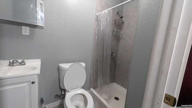 bathroom featuring a textured wall, a stall shower, vanity, and toilet