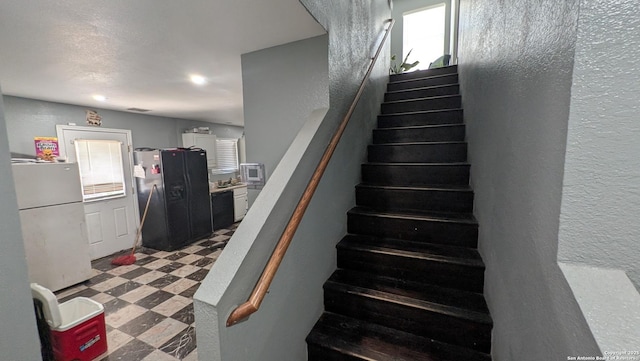 stairs featuring a textured wall and tile patterned floors